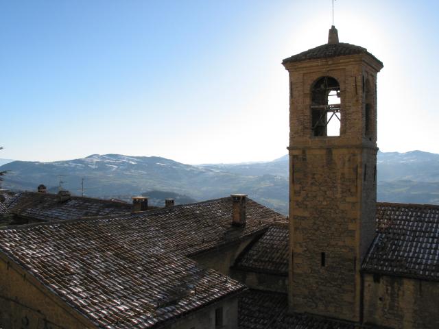Roofs, sun behind bell tower, and distant mountains