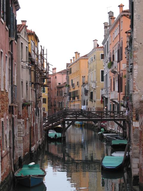 Canal, bridge between buildings, and boats