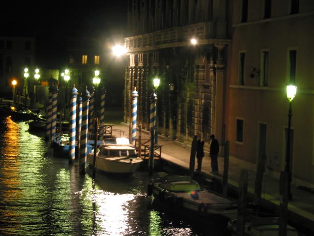 Nighttime view of people and boats under lamps, Venezia