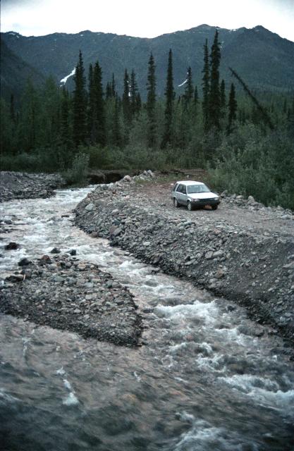 car on gravel bank by rushing river, just off Dempster Highway