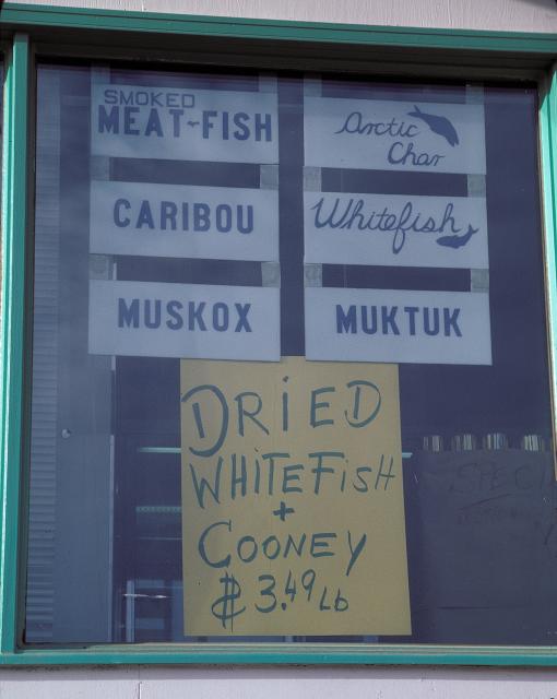 store window advertising Caribou, Muskox, Muktuk, Arctic Char, Whitefish, and smoked meat-fish